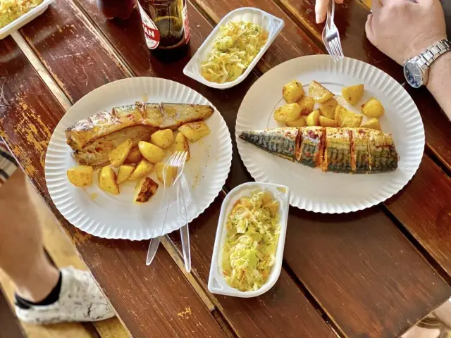 Dwa talerze z pieczonymi makrelami i ziemniakami, obok surówka i butelka napoju.